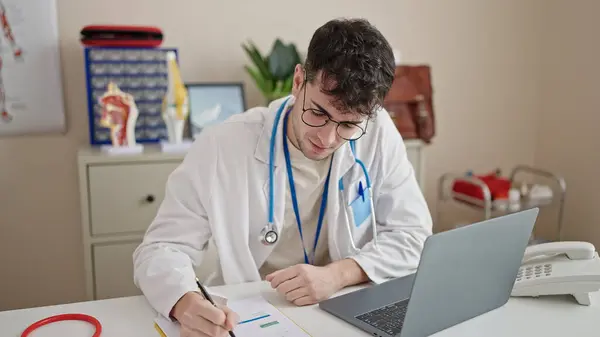 Jovem Hispânico Homem Médico Usando Laptop Escrever Documentos Clínica — Fotografia de Stock