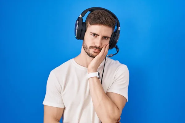 一个留着胡子的西班牙男人 戴着耳机听音乐 满脑子疲惫 对双臂交叉的抑郁症感到厌烦 — 图库照片