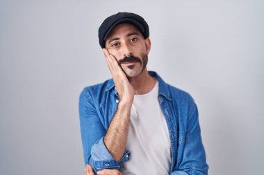 Hispanic man with beard standing over isolated background thinking looking tired and bored with depression problems with crossed arms. 