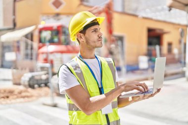 Young hispanic man architect using laptop at park
