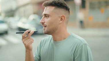 Young hispanic man talking on smartphone with serious expression at street