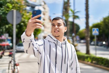 Young man smiling confident making selfie by the smartphone at street