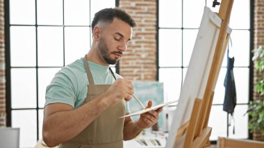 Sanat stüdyosunda genç Arap ressam ciddi bir yüz çiziyor.