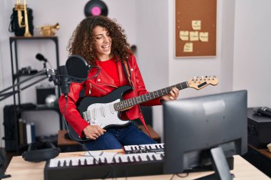Genç İspanyol kadın müzisyen müzik stüdyosunda elektro gitar çalıyor.