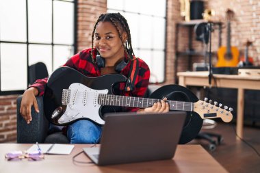 Afrikalı Amerikalı kadın müzisyen müzik stüdyosunda elektronik gitar dersi alıyor.