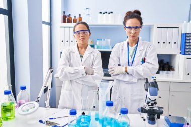 Laboratuvardaki genç anne ve kızı şüpheci ve gergin. Yüzünde çapraz kollarla tasvip etmeyen bir ifade. negatif kişi. 