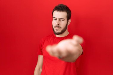 Gündelik kırmızı tişört giyen, neşeli gülümseyen, yardım eli uzatan ve kabul gören İspanyol genç bir adam.. 