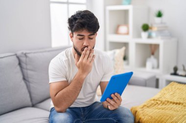 Kanepede oturan dokunmatik sakallı, esnemekten sıkılmış, ağzı eliyle kapatan İspanyol bir adam. Huzursuz ve uykulu.. 