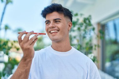 Genç İspanyol adam gülümsüyor. Kendine güveniyor. Sokakta akıllı telefondan konuşuyor.