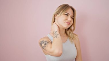 İzole edilmiş pembe arka planda boyun ağrısı çeken genç sarışın kadın.