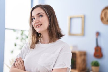 Young woman smiling confident standing with arms crossed gesture at home