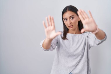Beyaz arka planda duran genç İspanyol kadın el ve parmaklarıyla çerçeve yapıyor, kamera bakış açısı. 