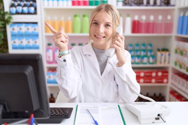 Eczanede çalışan beyaz bir kadın telefonda konuşurken yüzünde kocaman bir gülümseme vardı. Kameraya el ile işaret ediyordu.. 