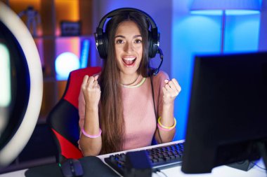 Video oyunları oynayan genç İspanyol kadın şaşırdı ve şaşırdı. Kollarını kaldırdı ve gözlerini açtı. Kazanan konsept. 