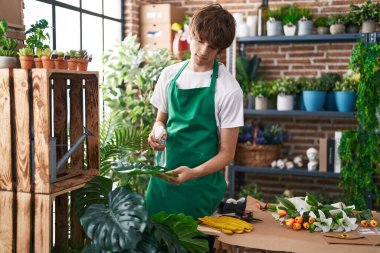 Çiçekçide çalışan sarışın bir çiçekçi.