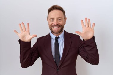 Sakallı ve kravatlı orta yaşlı bir iş adamı on numaralı parmaklarını gösterip gösterirken kendinden emin ve mutlu bir şekilde gülümsüyor.. 