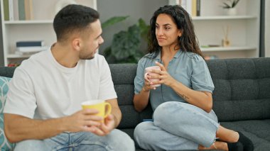 Man and woman couple sitting on sofa drinking coffee at home