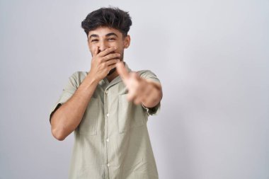 Beyaz arka planda sakallı bir Arap sana gülüyor, eli ağzında kamerayı işaret ediyor, utanç ifadesi takınıyor. 