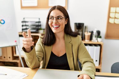 Genç, güzel, İspanyol bir iş kadını masada oturmuş ofiste konuşuyor.
