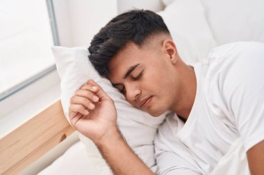 Genç İspanyol adam yatakta uzanıp yatak odasında uyuyor.