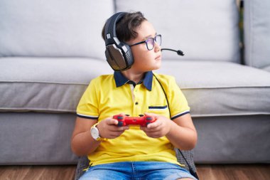 Yanında kulaklık takan, profil pozu veren, kendine güveni tam bir gülümsemeyle video oyunu oynayan genç İspanyol çocuk.. 