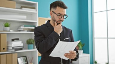 Genç Arap iş adamı büroda düşünen belgeler okuyor.