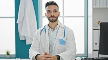 Klinikte ciddi bir ifadeyle masada oturan genç İspanyol doktor.