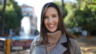 Güzel İspanyol kadın parkta kendinden emin gülümsüyor.