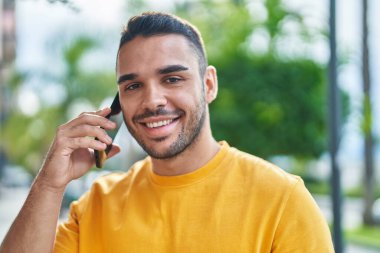Genç İspanyol adam gülümsüyor. Kendine güveniyor. Sokakta akıllı telefondan konuşuyor.