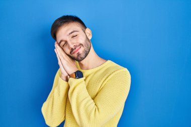 Mavi arka planda dikilen İspanyol adam uyuyordu. Yorgun düşler görüyordu ve elleriyle poz veriyordu. Gözleri kapalı gülümsüyordu.. 