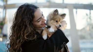 Parkta kendinden emin bir şekilde gülümseyen köpeği olan genç İspanyol kadın.