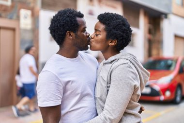African american man and woman couple hugging each other and kissing at street