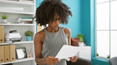 Afrika kökenli Amerikalı iş kadını ofiste evrak okuyor.