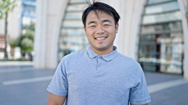  Gülümsüyor, kendine güveniyor.