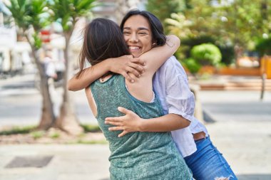 Two women mother and daughter smiling confident hugging each other at park