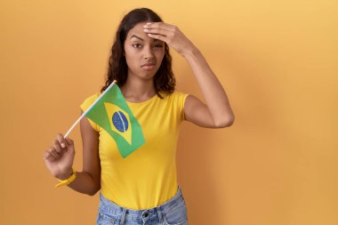 Elinde Brezilya bayrağı tutan genç İspanyol kadın. Alnındaki bir sorun yüzünden endişeli ve stresli. Kriz için endişeli. 
