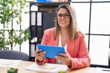 Young hispanic woman business worker using touchpad working at office