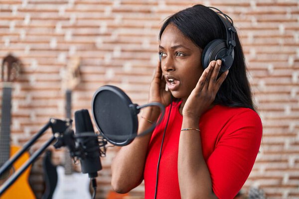 Young african american woman artist singing song at music studio