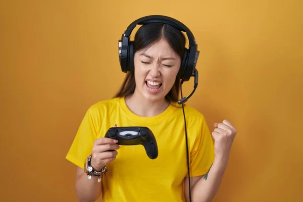 中国年轻女子抱着控制器玩电子游戏时 非常高兴而兴奋地举起双臂做着获胜的手势 笑着喊着要成功 庆祝概念 — 图库照片