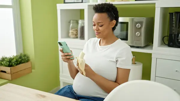 Junge Schwangere Isst Banane Mit Smartphone Esszimmer — Stockfoto