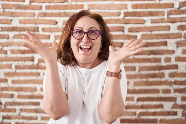 Mujer Mayor Con Gafas Pie Sobre Pared Ladrillos Celebrando Loco —  Fotos de Stock