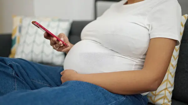 Junge Schwangere Sitzt Mit Smartphone Hause Auf Sofa — Stockfoto
