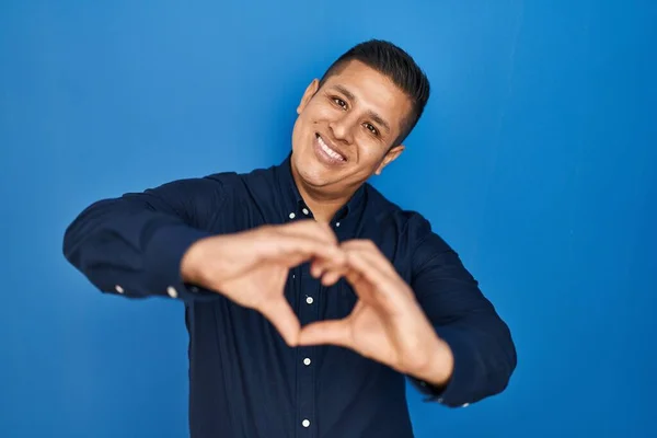 Jovem Hispânico Sobre Fundo Azul Sorrindo Amor Fazendo Forma Símbolo — Fotografia de Stock
