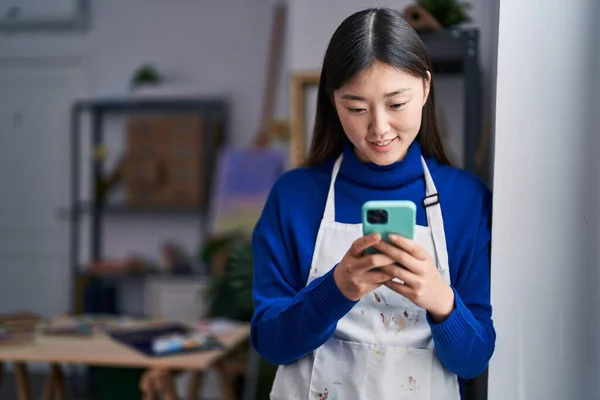 Chinese woman artist smiling confident using smartphone at art studio