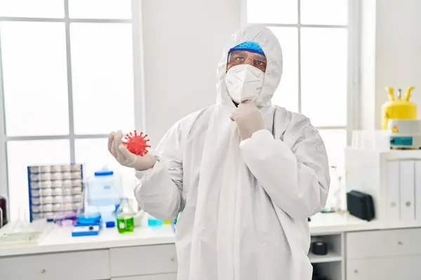 Jovem Hispânico Trabalhando Laboratório Cientista Segurando Brinquedo Vírus Rosto Sério — Fotografia de Stock