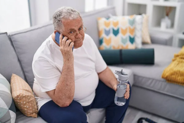 Medelålders Gråhårig Man Talar Smartphone Innehav Flaska Vatten Hemma — Stockfoto