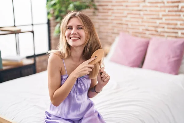 Young Blonde Woman Combing Hair Sitting Bed Bedroom — Stockfoto