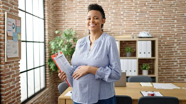 年轻的怀孕女工在办公室触摸肚脐夹板 — 图库照片