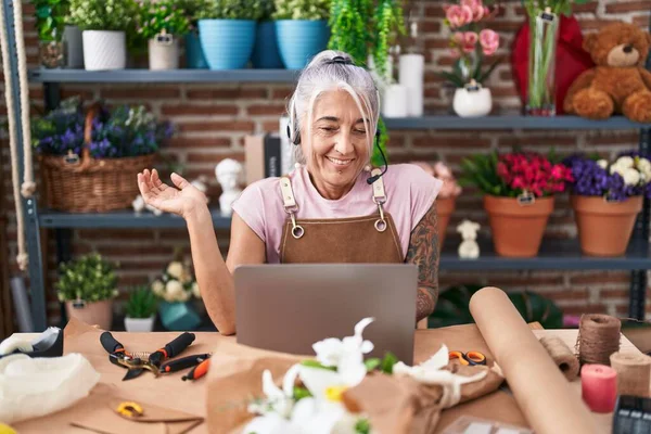 Middle age woman with tattoos working at florist shop doing video call celebrating achievement with happy smile and winner expression with raised hand
