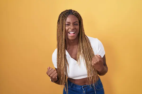 Afroamerykanka Plecionymi Włosami Stojąca Żółtym Tle Bardzo Szczęśliwa Podekscytowana Wykonując — Zdjęcie stockowe